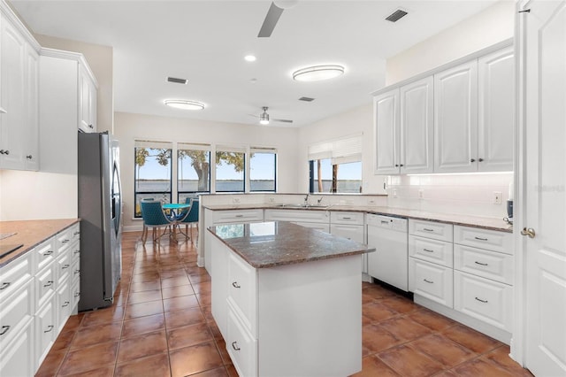 kitchen featuring dishwasher, ceiling fan, stainless steel fridge, a kitchen island, and white cabinetry