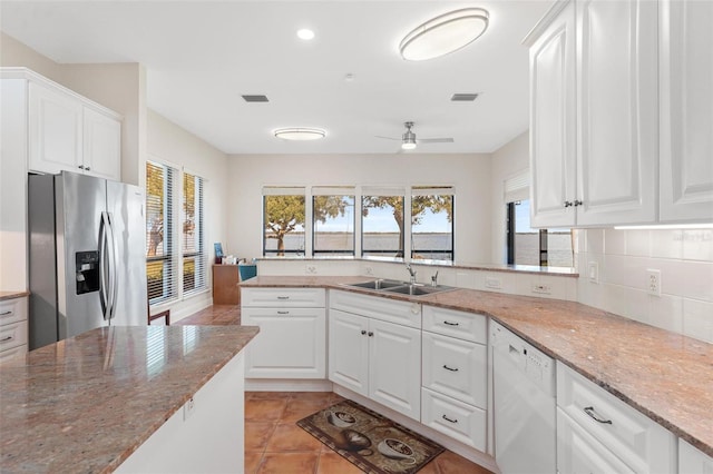 kitchen featuring white cabinets, stainless steel fridge, and sink