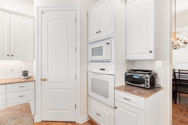 kitchen featuring decorative light fixtures, white cabinetry, white appliances, and backsplash