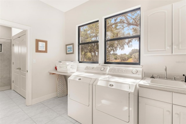 laundry room with washing machine and clothes dryer, sink, light tile patterned floors, and cabinets