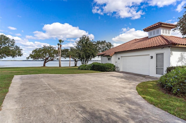 view of property exterior featuring a garage, a water view, and a yard