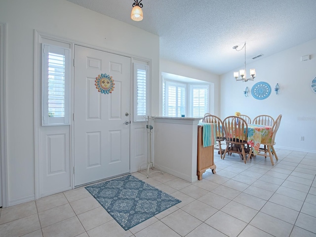 entrance foyer featuring a notable chandelier, light tile patterned flooring, lofted ceiling, and a textured ceiling