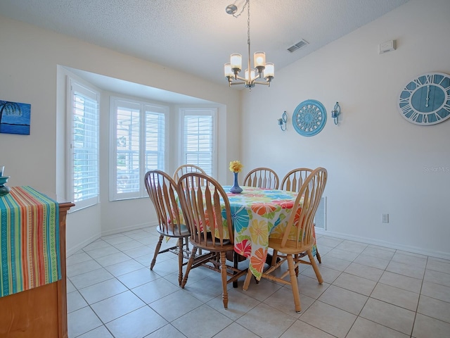 dining space with light tile patterned floors, a textured ceiling, and an inviting chandelier