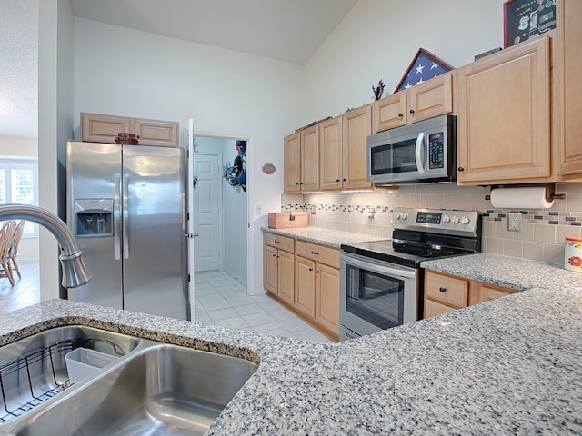 kitchen featuring sink, tasteful backsplash, light tile patterned floors, light brown cabinetry, and appliances with stainless steel finishes