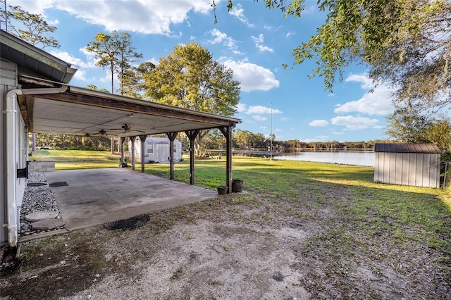 view of yard with a patio area, a water view, and a storage shed