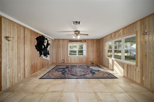 interior space with wood walls and ceiling fan