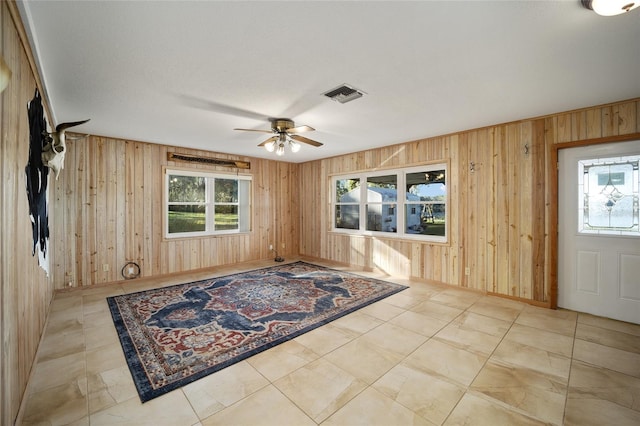 foyer with ceiling fan and wood walls