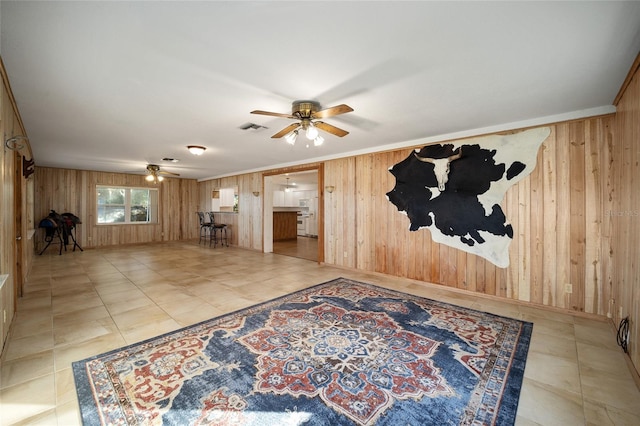 living room featuring ceiling fan and wood walls