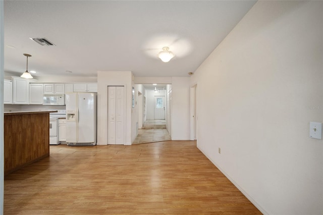 interior space featuring white cabinets, decorative light fixtures, white appliances, and light hardwood / wood-style flooring