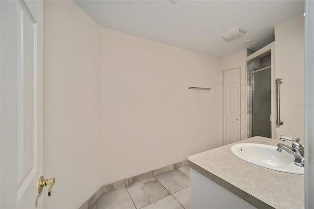 bathroom with tile patterned flooring, vanity, and walk in shower