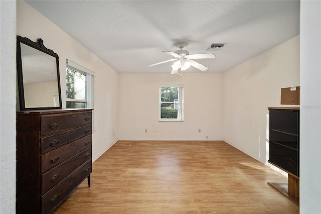 bedroom with ceiling fan, light hardwood / wood-style flooring, and a textured ceiling