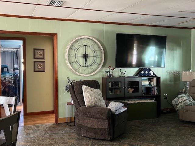 living area featuring ornamental molding and wood walls