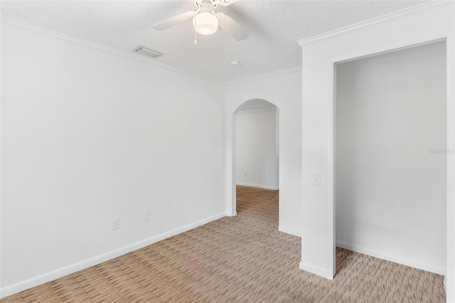 spare room featuring light carpet, a textured ceiling, ceiling fan, and ornamental molding