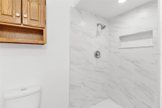 bathroom featuring toilet and a tile shower