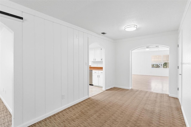 spare room featuring light carpet, a textured ceiling, and ornamental molding