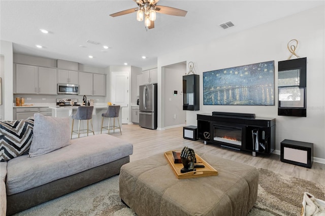 living room featuring light hardwood / wood-style floors and ceiling fan