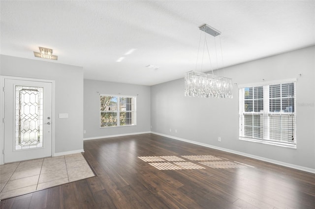 entryway with dark hardwood / wood-style flooring, a textured ceiling, and an inviting chandelier