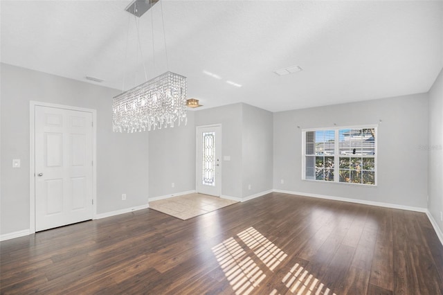 unfurnished living room with a chandelier and dark hardwood / wood-style floors