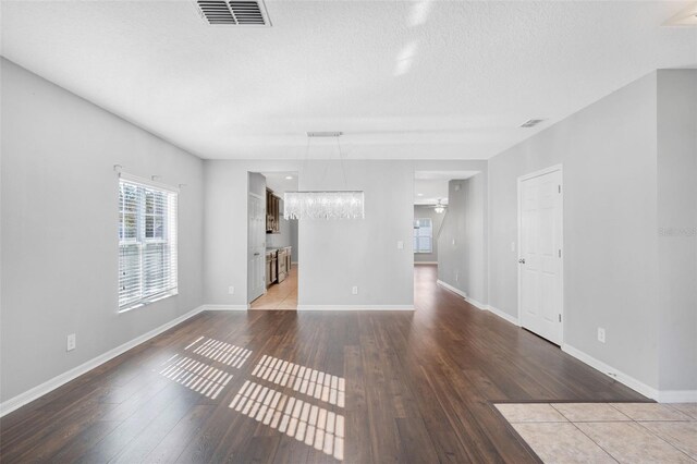 spare room featuring hardwood / wood-style floors, a textured ceiling, and an inviting chandelier