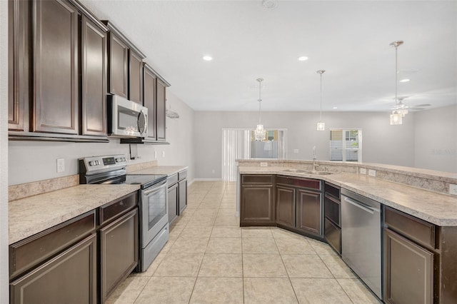 kitchen with appliances with stainless steel finishes, dark brown cabinets, ceiling fan, sink, and hanging light fixtures