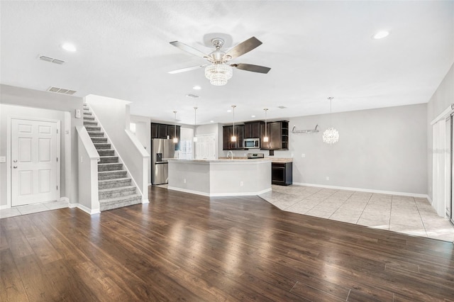 unfurnished living room with hardwood / wood-style floors, ceiling fan with notable chandelier, and sink