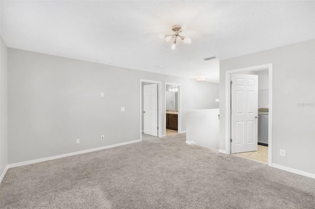 empty room featuring light colored carpet and an inviting chandelier