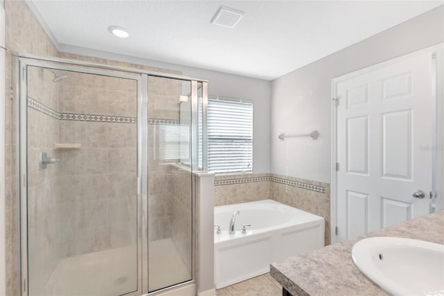 bathroom featuring plus walk in shower, a textured ceiling, vanity, and tile patterned floors