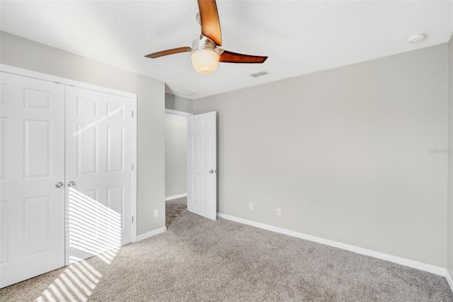 unfurnished bedroom featuring ceiling fan, light colored carpet, and a closet