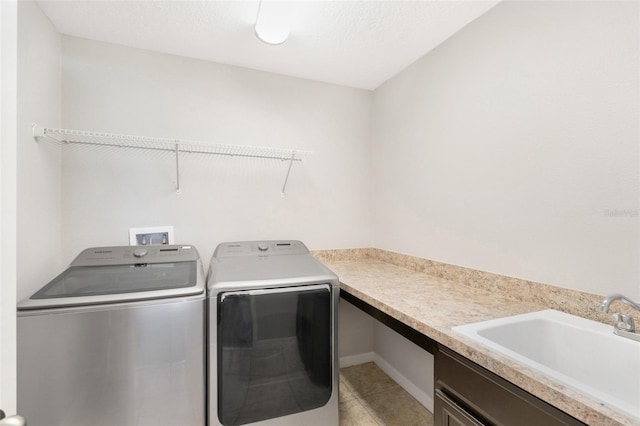 laundry room featuring a textured ceiling, washer and dryer, light tile patterned floors, and sink