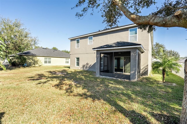 rear view of property featuring a yard and a sunroom