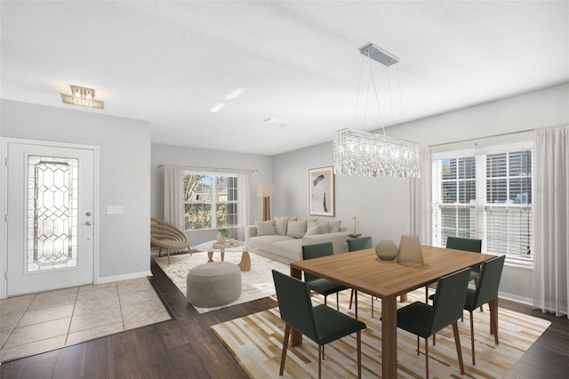 dining area featuring a textured ceiling, hardwood / wood-style flooring, and an inviting chandelier