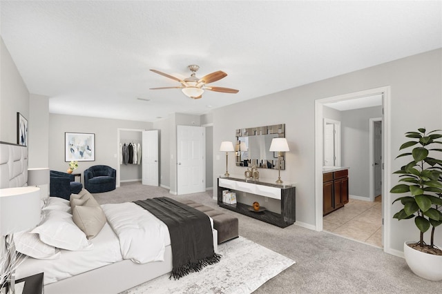 bedroom with ceiling fan, light carpet, connected bathroom, and a closet