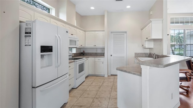 kitchen featuring white cabinets, white appliances, and a wealth of natural light