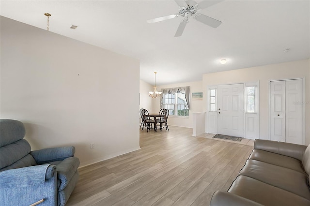 living room featuring ceiling fan with notable chandelier and light wood-type flooring