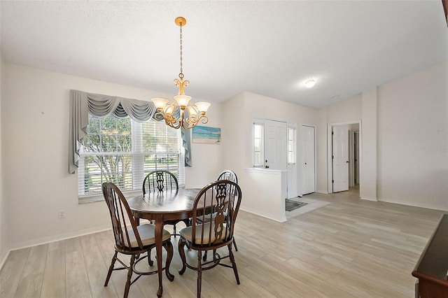 dining space with light hardwood / wood-style floors, lofted ceiling, and an inviting chandelier