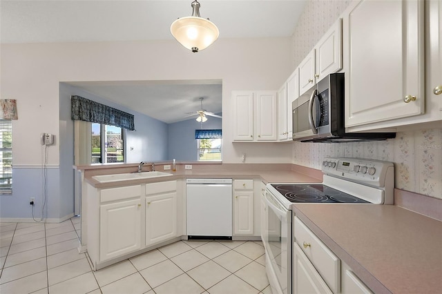 kitchen with white appliances, white cabinets, sink, vaulted ceiling, and kitchen peninsula