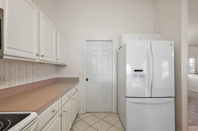 kitchen with white cabinetry, light tile patterned floors, and white refrigerator with ice dispenser