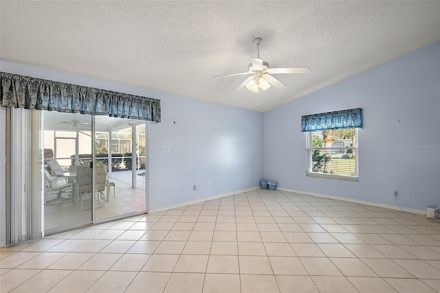 empty room with a textured ceiling, ceiling fan, light tile patterned flooring, and lofted ceiling