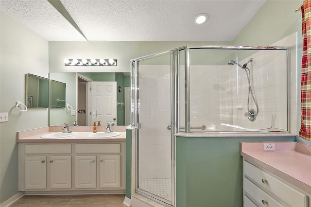 bathroom featuring a textured ceiling, vanity, and a shower with door