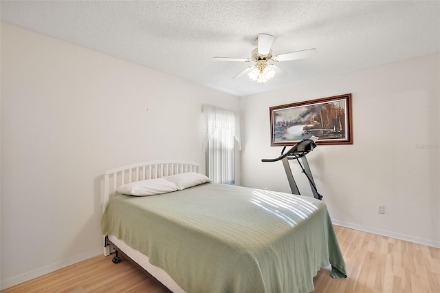 bedroom with ceiling fan, light wood-type flooring, and a textured ceiling