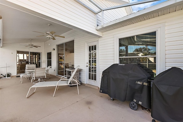 view of patio featuring glass enclosure, area for grilling, and ceiling fan