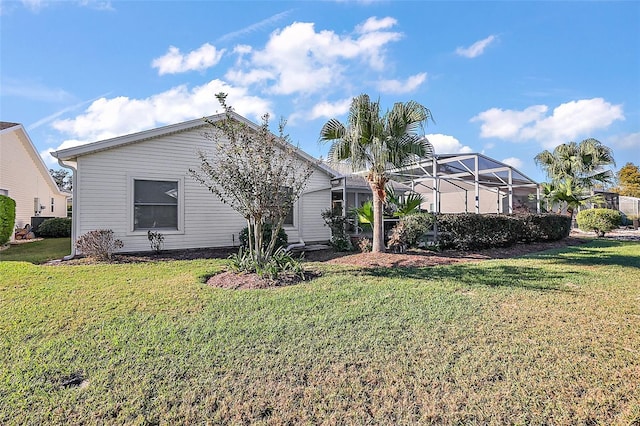 rear view of property featuring glass enclosure and a yard