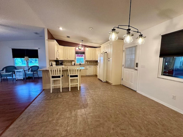 kitchen featuring decorative light fixtures, backsplash, white fridge, and white cabinetry