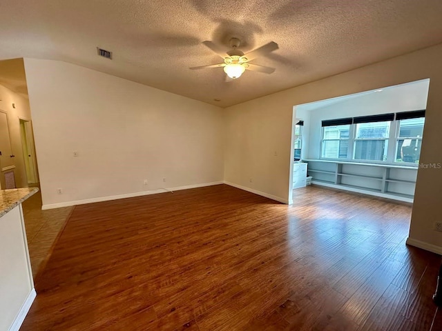 empty room featuring ceiling fan, dark wood-type flooring, and a textured ceiling