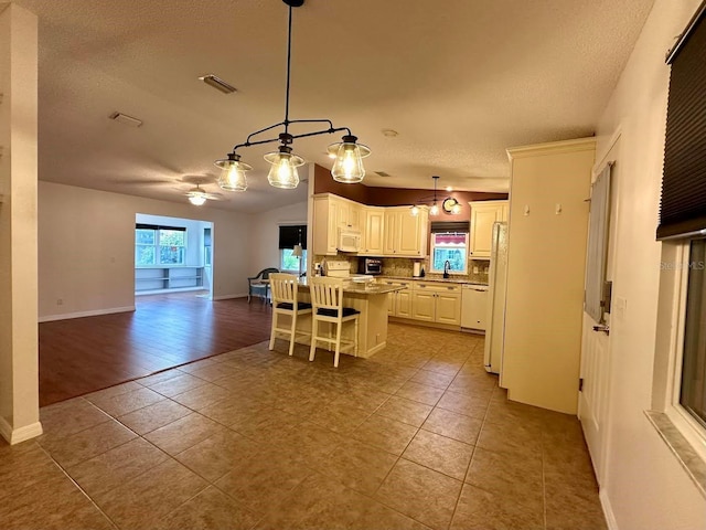 kitchen with pendant lighting, a center island, white appliances, a kitchen breakfast bar, and ceiling fan