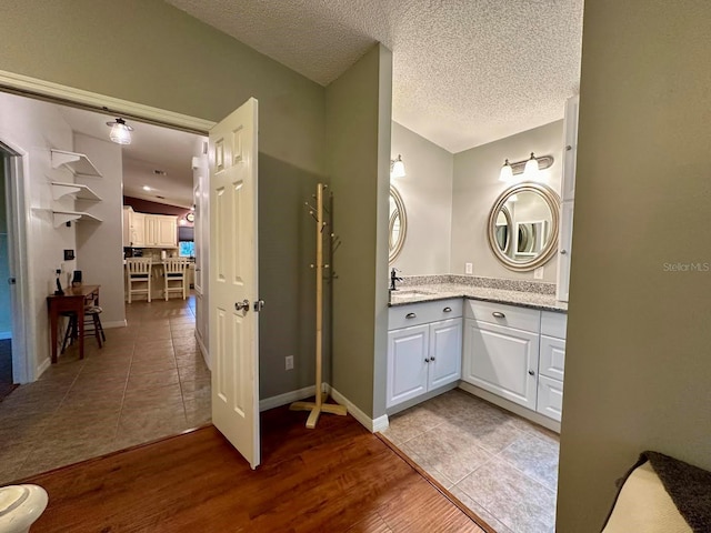 bathroom with vanity, wood-type flooring, and a textured ceiling