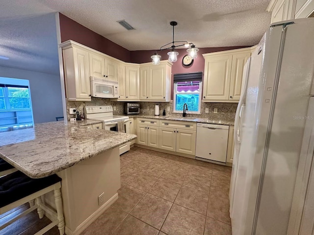 kitchen featuring white appliances, light tile patterned floors, decorative light fixtures, a kitchen bar, and kitchen peninsula