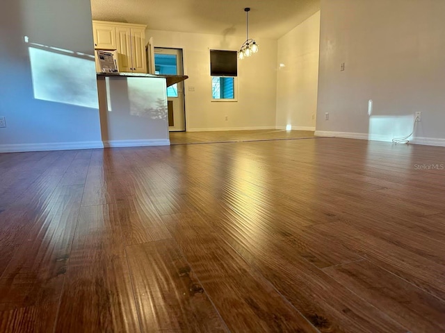 unfurnished living room with an inviting chandelier and dark wood-type flooring