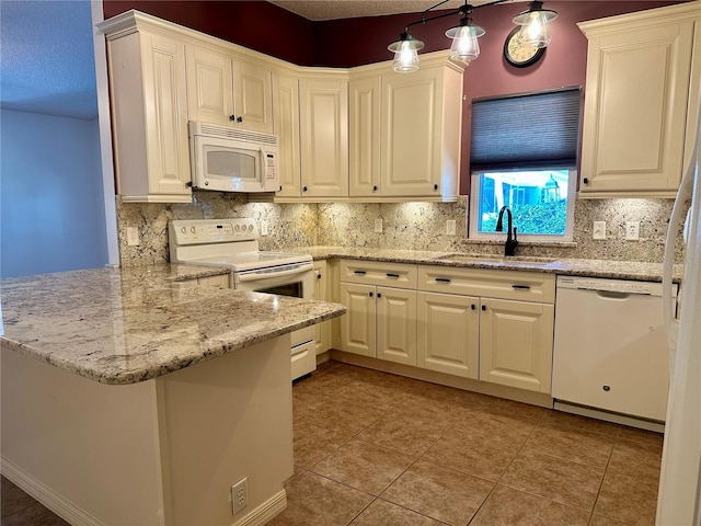 kitchen with sink, white appliances, hanging light fixtures, light stone counters, and kitchen peninsula