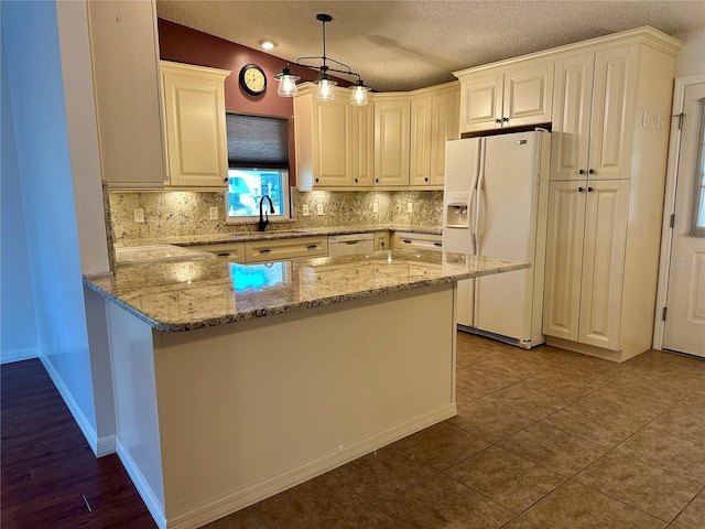 kitchen with pendant lighting, sink, white appliances, light stone countertops, and kitchen peninsula